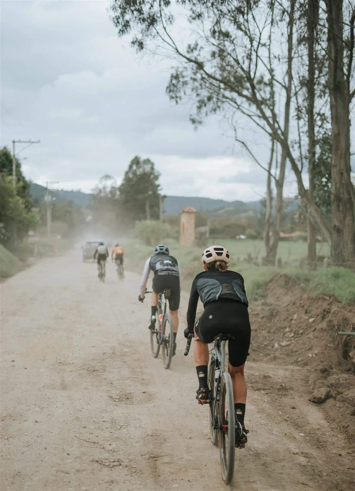 Grupo de ciclistas de gravel levantando polvo en un camino rural, Rural Gravel Tour