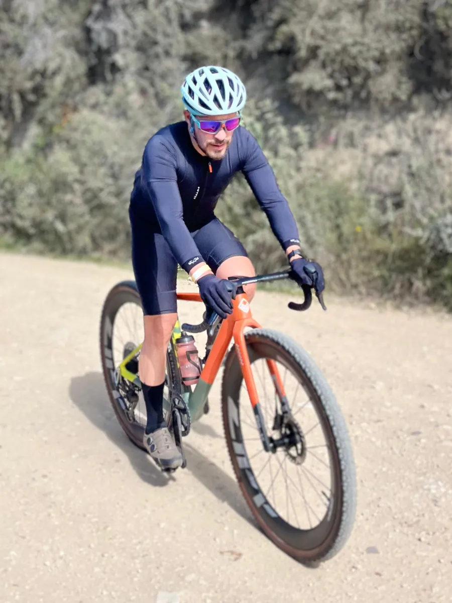 Ciclista en bicicleta de gravel naranja por un camino destapado en Guasca